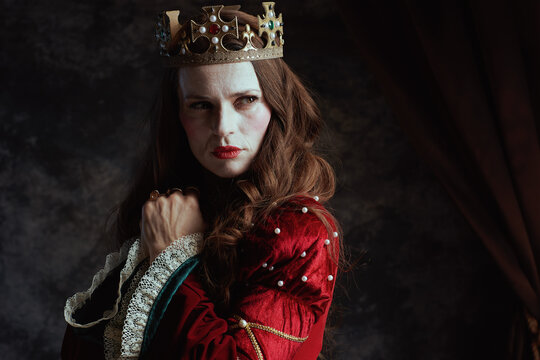 pensive medieval queen in red dress with white makeup
