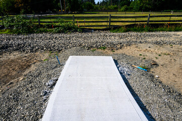 Freshly poured cement sidewalk leading to nowhere surrounded by dirt and gravel, new residential...