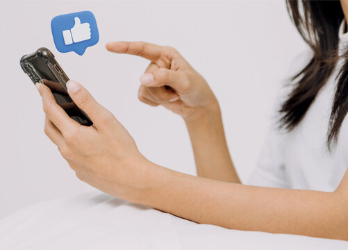 J&oacute;ven mujer tecleando su celular dando like. Dale me gusta.