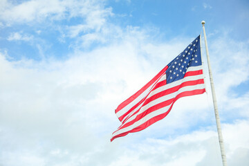 US flag waving in the wind against a blue sky. Symbol of freedom, unity, and national pride. Perfect for patriotic themes