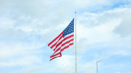 US flag waving in the wind against a blue sky. Symbol of freedom, unity, and national pride. Perfect for patriotic themes