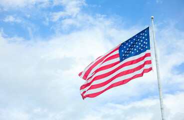 US flag waving in the wind against a blue sky. Symbol of freedom, unity, and national pride. Perfect for patriotic themes