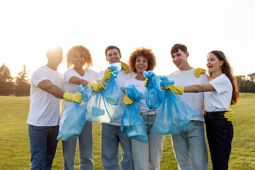 multiracial group of people volunteers in gloves with garbage bags collect garbage and plastic in the park