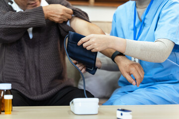 Nurses or caregivers take care of elderly by helping to check their blood pressure