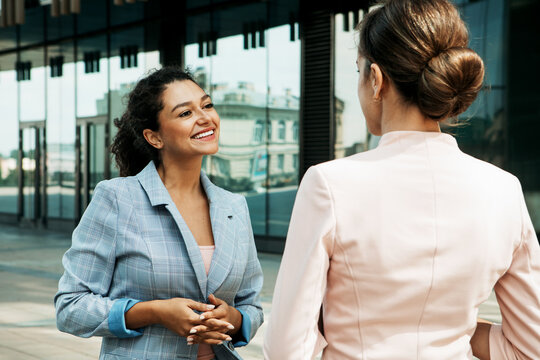 Two business women having a casual meeting or discussion near a modern office