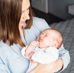 Loving mom carying of her newborn baby at home.