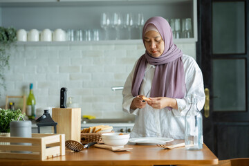 Fototapeta na wymiar A Muslim woman is preparing to cook breakfast for her family. At the beautiful kitchen in her house, having fun woman with hijab preparing dinner, Islamic woman Enjoying Doing Homemade.