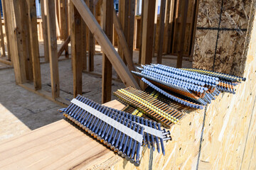 Stacks of framing nails sitting on the windowsill of a house under construction in a new residential community under construction
