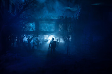 Silhouette of person standing in the dark forest with light. Horror halloween concept.