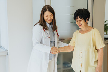 Fototapeta premium Doctor visits elderly woman at clinic, analyzing diagnosis and discussing medical results. Patient receives treatment and professional care.