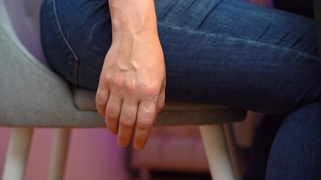 Woman in jeans sitting on chair at table loses consciousness and drops bitten apple. Insensitive female hand falls powerlessly and drops fruit