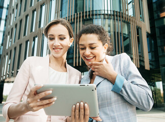 Portrait of two businesswomen looking at digital tablet and discussing new project.