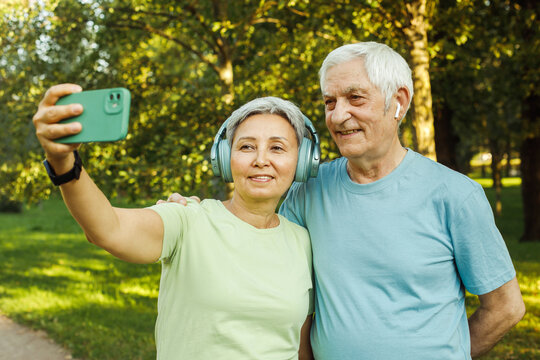 Happy senior couple taking selfie sitting in park outdoors. Love togetherness and acive seniors vitality concept