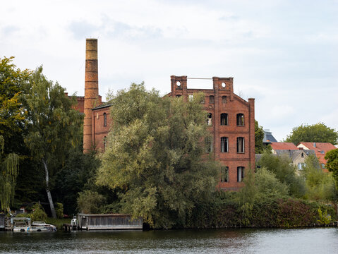 MALCHOW, GERMANY - 1. October 2023: Abandoned factory building next to the lake. The old industrial house with a chimney was former a VEB company for spinning and weaving textiles.