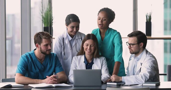 Diverse medical workers take part in teamwork or concilium, hospital staff working together in clinic office using laptop, discuss disease, consider recovery prognosis, share opinion. Medicine, tech