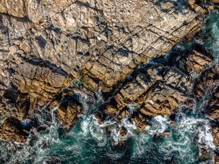 downward drone view of waves crashing on rocks