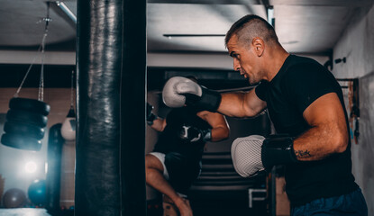 Action of a boxing martial arts fighter training on a punching bag in the gym