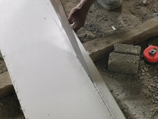Worker cutting a white standard plaster ceiling board panel.