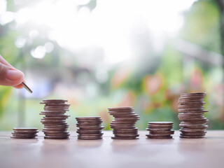Close up hand putting coin in stack of coins, The concept of saving money, Financial, Investment and Business growing.