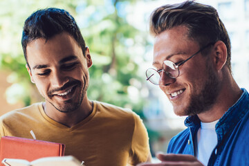 Happy young men reading notepad on street