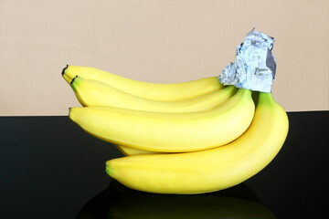 isolated fresh organic ripe yellow banana fruit protection or preservation from turning brown and keep fresh longer with aluminium foil cap wrap    - obrazy, fototapety, plakaty