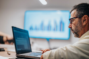 Multicultural business team collaborating on architectural blueprints in a conference room. Diverse executives discussing construction plans in a board room meeting.