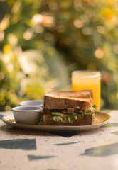 sandwich de Ramon con lechuga y un jugo de naranja de fondo 
