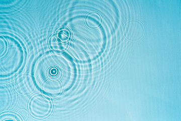 Raindrops on the surface of the water. Swimming pool water background with drops and ripples from...