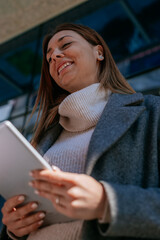 Blonde businesswoman holding a tablet and smiling while having fun conversation with her colleagues. Low angle view shot