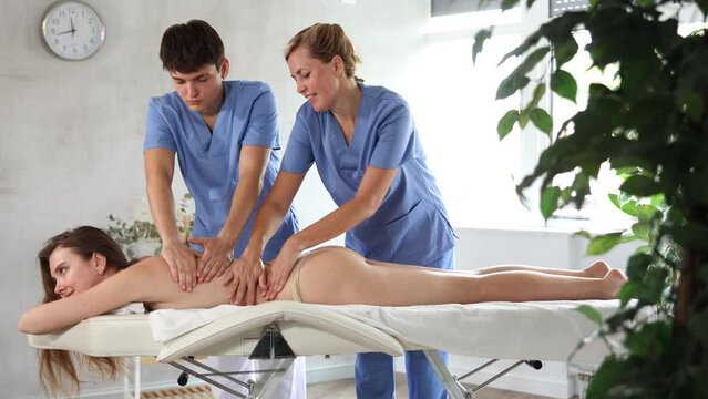Cropped hands of two female and male physiotherapists massage of unrecognizable woman. Close-up. High quality 4k footage