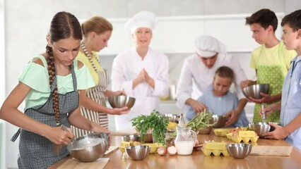 Girl in apron learning to cook at cooking master class