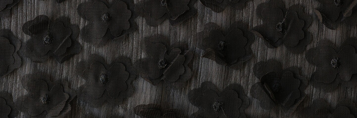 Black flowers attached to grey fabric designed for clothing - obrazy, fototapety, plakaty