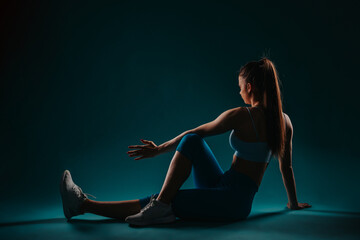 Confident Female Fitness Model: Powerful Muscular Girl Exercising in Dark Studio