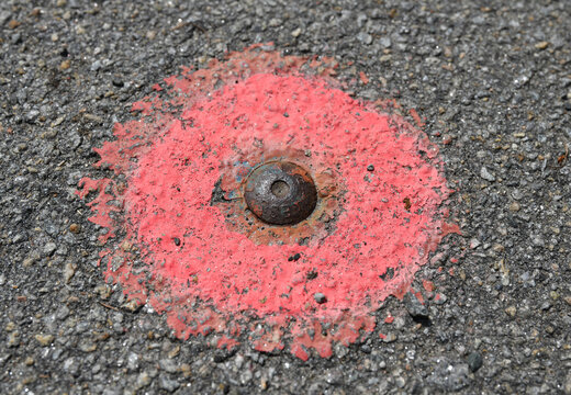 rostiger Messpunkt auf Asphalt
