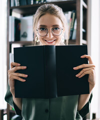 Cheerful lady standing with open book and smiling