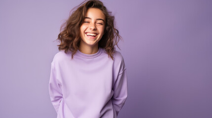 Happy teen girl, smiling and laughing, wearing a solid lavender sweatshirt. solid lavender background similar to the dress color.