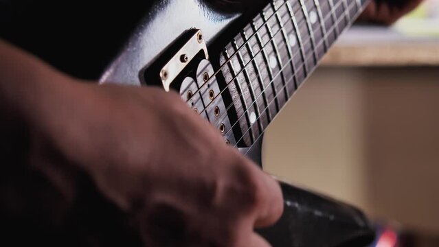 Close-up of a guitarist's hand with a pick playing an electric guitar. Man playing an old black guitar. Rehearsing and learning new songs