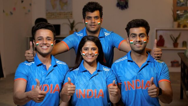 Indian friends dressed in Indian cricket team jersey posing for the camera - thumbs-up gesture  jersey with India's name  painted Indian flag. Indian friends in their cricket jerseys with the India...