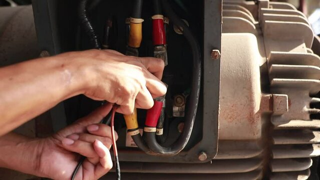 Stop checking the motor repairs : Closeup male electrician worker uses multimeter to check motor abnormalities 125 HP and measure electrical current at electric motor wiring terminals for safety.