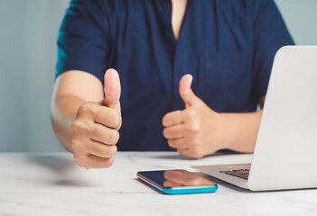 Businessman showing thumbs up to the success and best service while sitting at the table