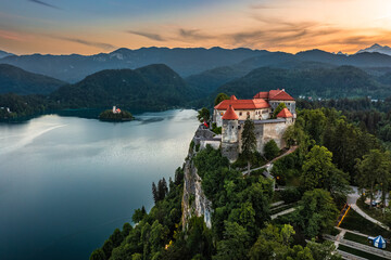 Bled, Slovenia - Aerial panoramic view of beautiful Bled Castle (Blejski Grad) with Lake Bled (Blejsko Jezero), the Church of the Assumption of Maria and colorful sunset sky over Julian Alps - obrazy, fototapety, plakaty