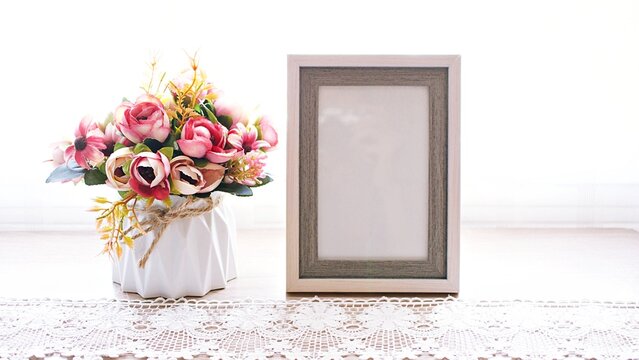 Photo frame with artificial flowers , Empty frame for letter with pink orange rose flowers background ,vintage style copy space ,romantic tone 