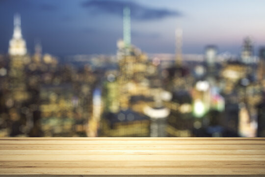 Empty tabletop made of wooden dies with blurry city view at dusk on background, template
