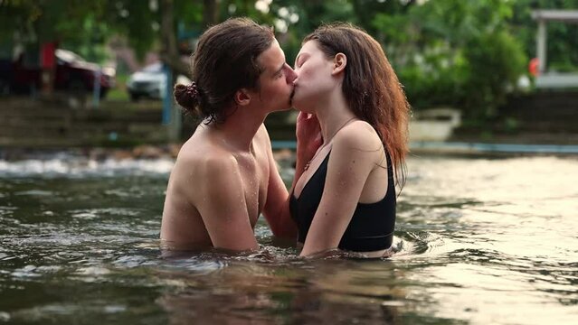 Happy romantic couple having vacation traveling in summer in nature and staying at a happy resort playing water in the stream standing kissing and hugging each other having the utmost 