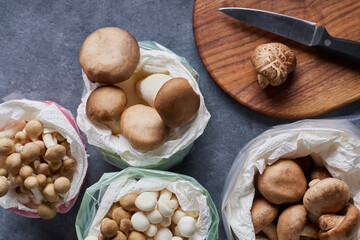 Top view close-up of group of mushrooms with cutting board, knife on blue-grey background.