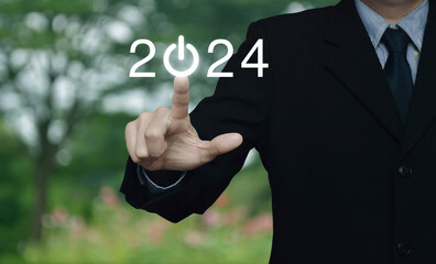 Businessman pressing 2024 start up business flat icon over blur flower and tree in park, Business happy new year 2024 success concept