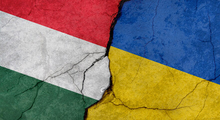 Hungary and Ukraine flags, concrete wall texture with cracks, grunge background, military conflict concept
