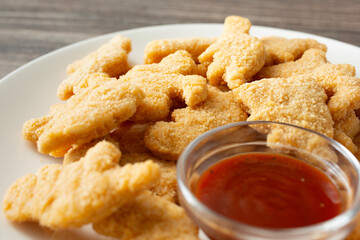 A closeup view of a plate of dinosaur chicken nuggets.