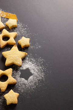 Vertical image of close up of christmas cookies with copy space and ribbon on black background