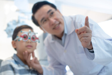 Optometrist used trial frame to check the boy's vision, point out something, selective focus at hand